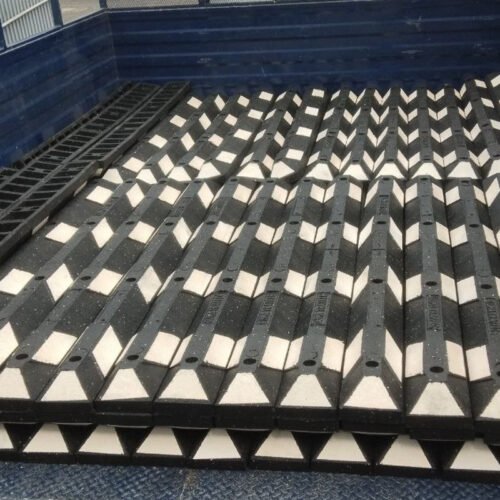Fila de topes de hule con reflejante instalados en un estacionamiento comercial